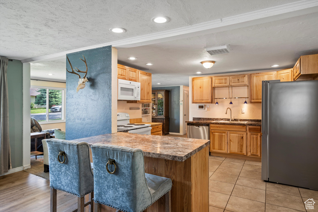 Kitchen with stainless steel appliances, a sink, a textured ceiling, a breakfast bar area, and a peninsula