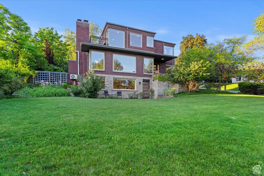 Back of property with a yard and brick siding