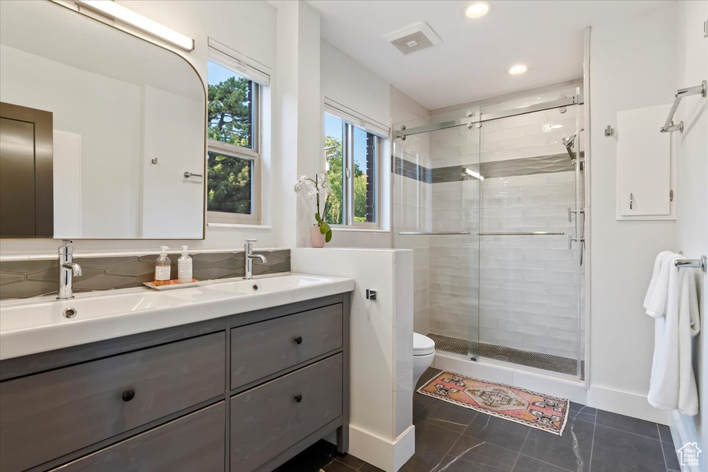 Full bath featuring double vanity, a stall shower, toilet, recessed lighting, and baseboards