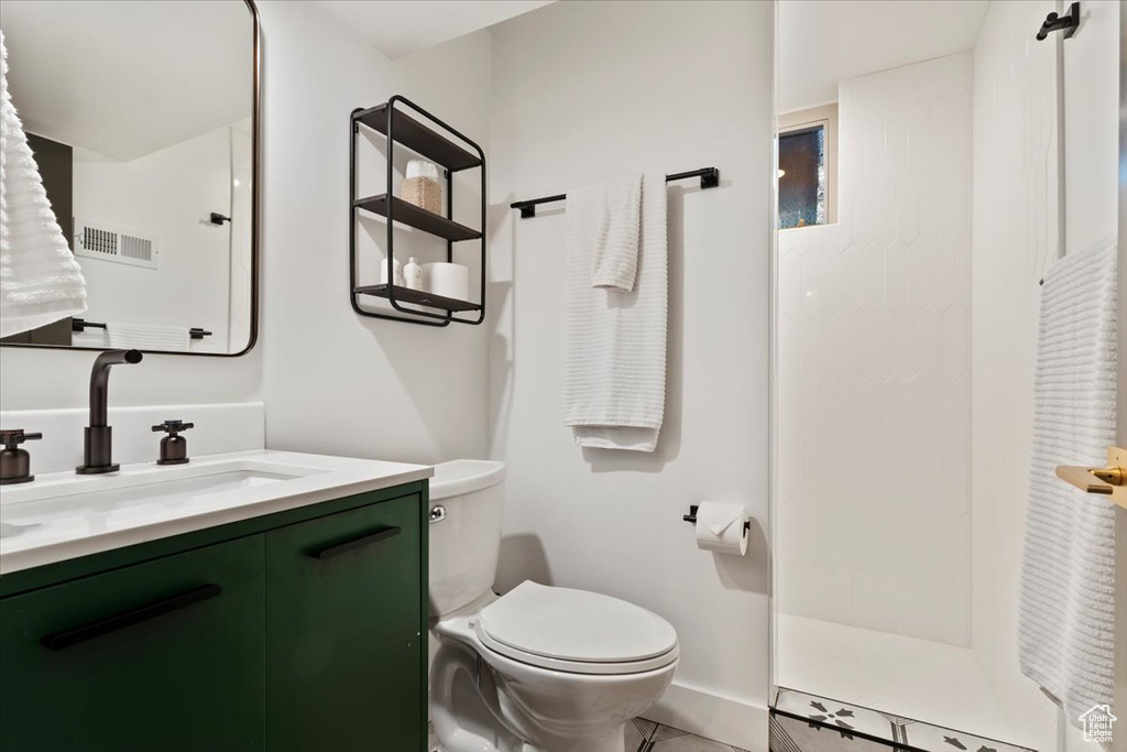 Bathroom featuring vanity, toilet, a walk in shower, baseboards, and tile patterned floors