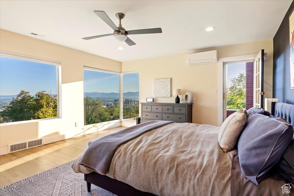 Bedroom featuring a wall unit AC, wood finished floors, access to outside, ceiling fan, and recessed lighting