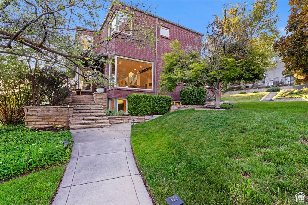 View of home's exterior with a lawn, stairway, and brick siding