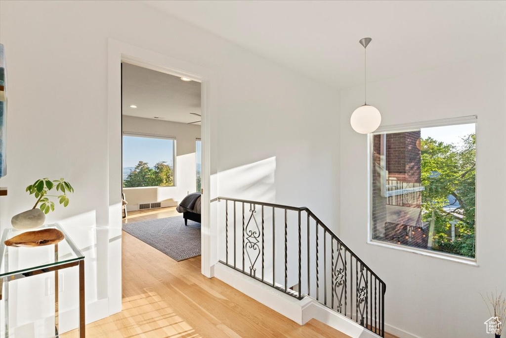 Hallway with an upstairs landing, light wood finished floors, and recessed lighting