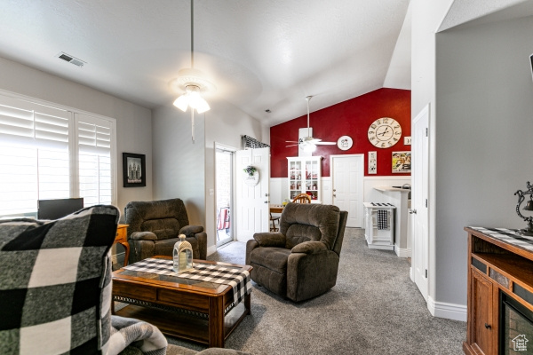 Carpeted living room featuring lofted ceiling, a ceiling fan, plenty of natural light, and baseboards