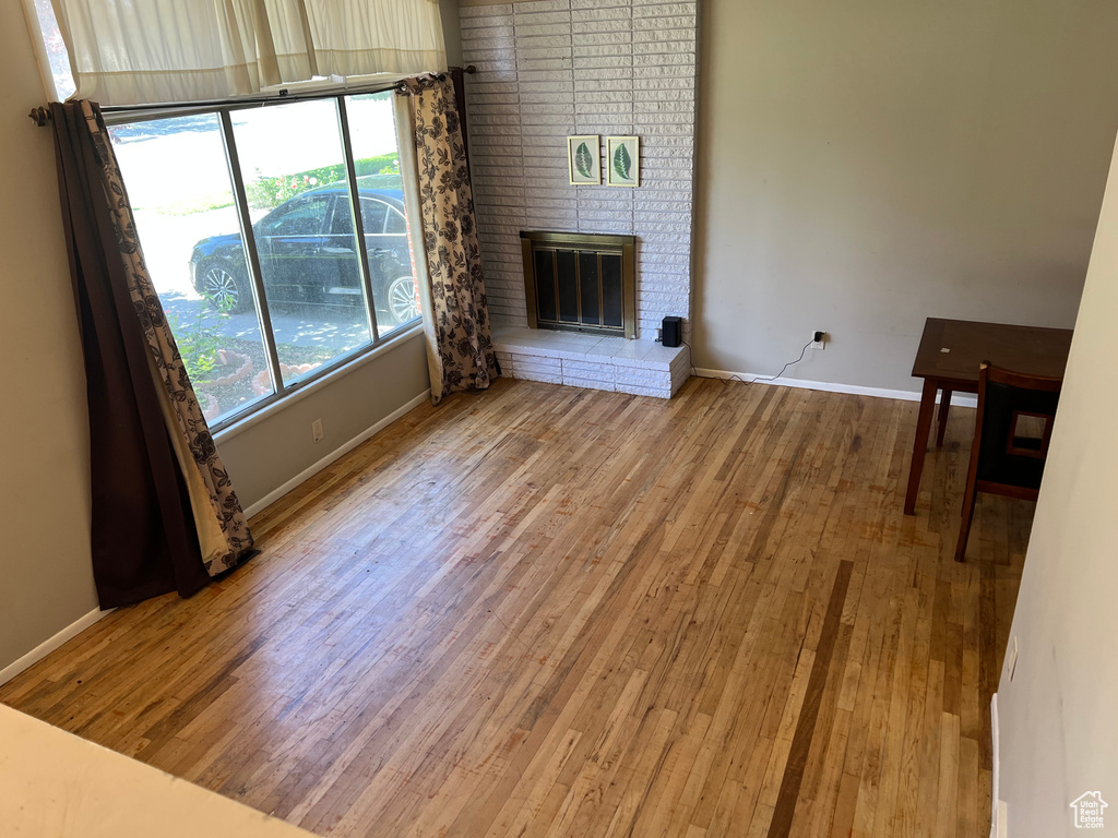 Unfurnished living room featuring wood finished floors, plenty of natural light, and baseboards