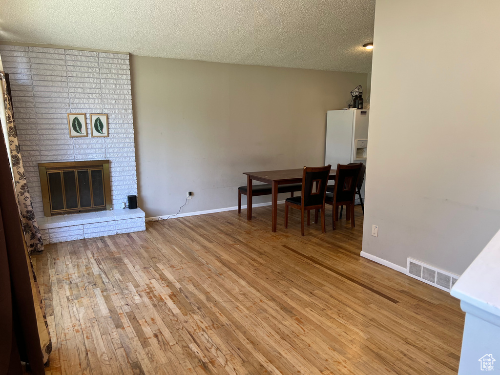 Unfurnished living room featuring light wood-style floors, a textured ceiling, baseboards, and a fireplace