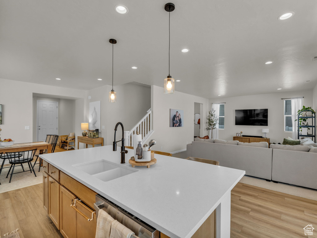 Kitchen featuring a sink, stainless steel dishwasher, light wood finished floors, recessed lighting, and light countertops