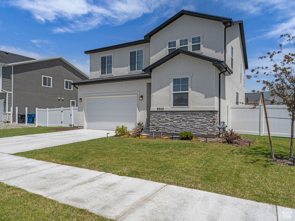 Traditional-style home featuring stucco siding, concrete driveway, a garage, and stone siding
