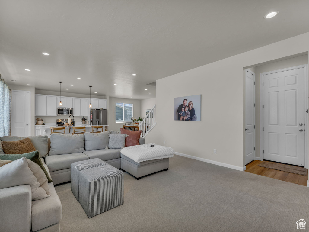 Living area featuring recessed lighting, stairs, baseboards, and light wood finished floors