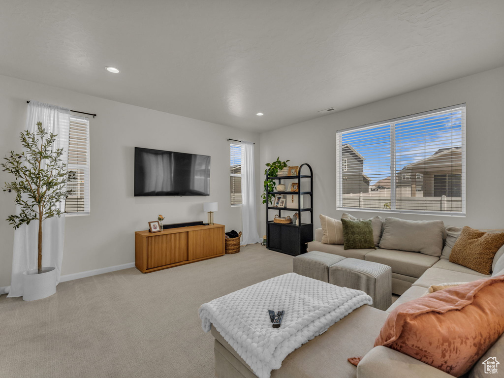Living area with light colored carpet, recessed lighting, and baseboards