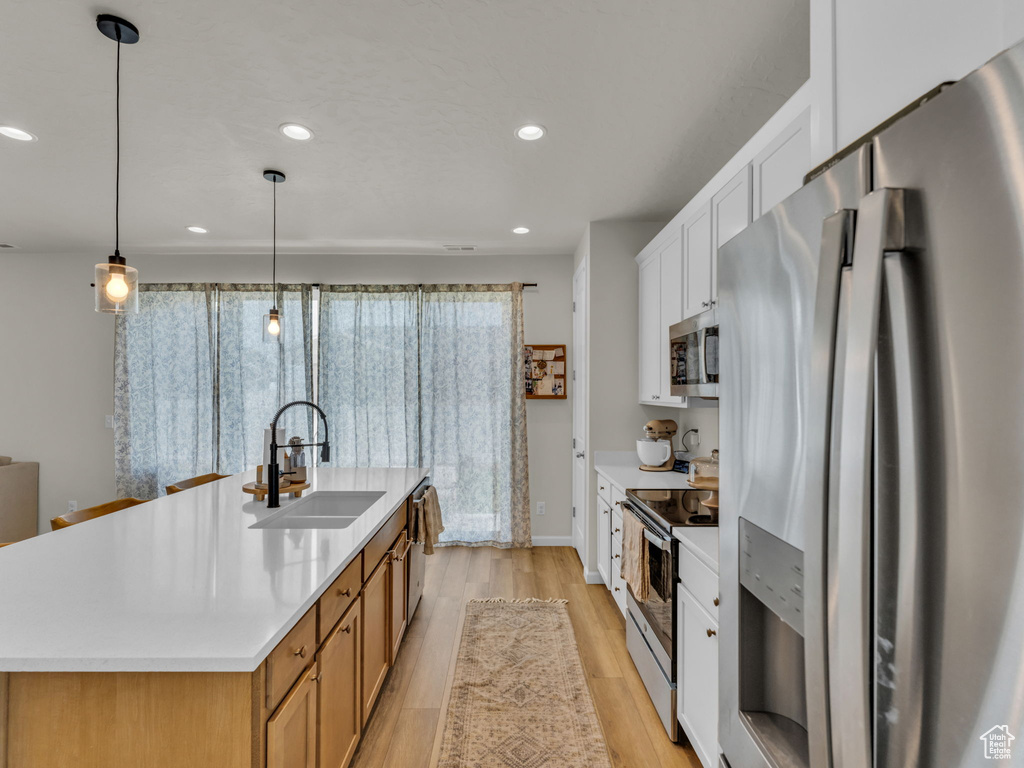 Kitchen featuring appliances with stainless steel finishes, a sink, light wood-style flooring, light countertops, and recessed lighting