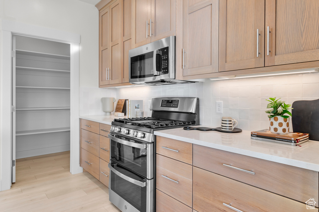 Kitchen featuring appliances with stainless steel finishes, tasteful backsplash, and light countertops