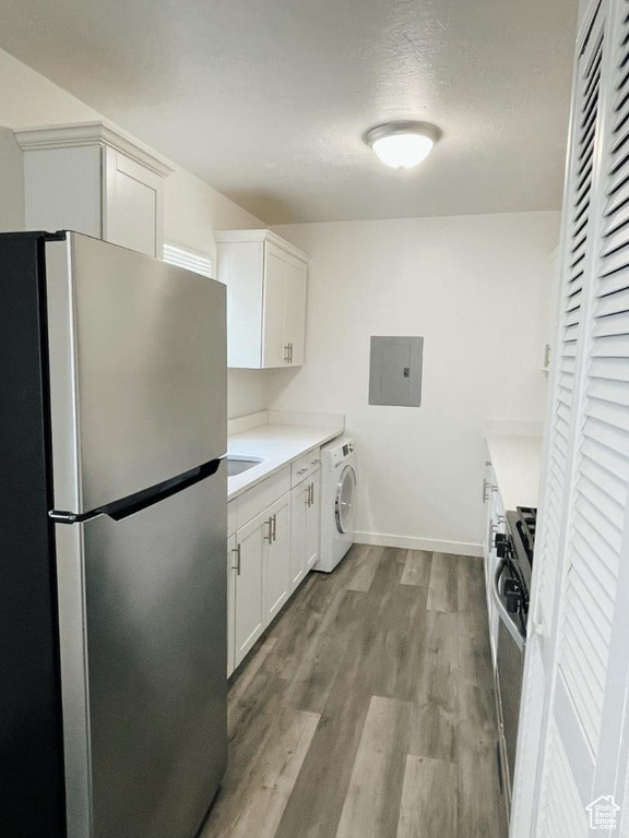 Kitchen featuring freestanding refrigerator, washer / clothes dryer, electric panel, and light countertops