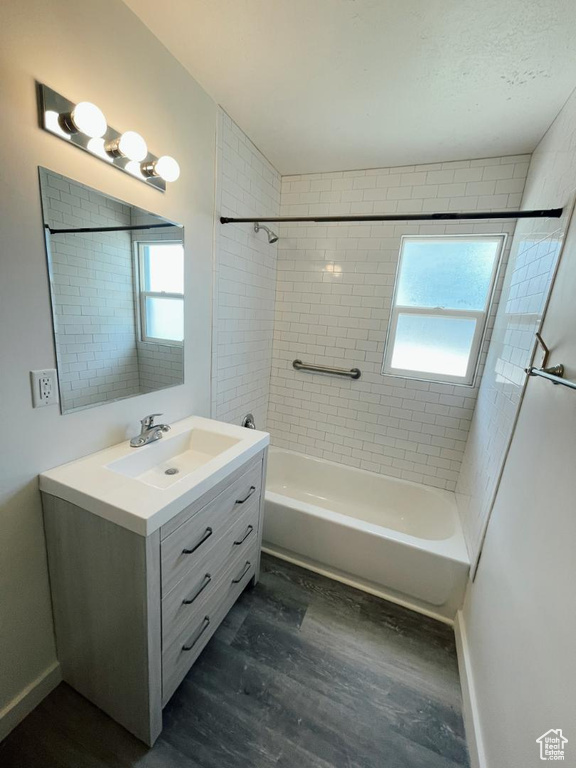 Full bathroom featuring wood finished floors, vanity,  shower combination, and baseboards