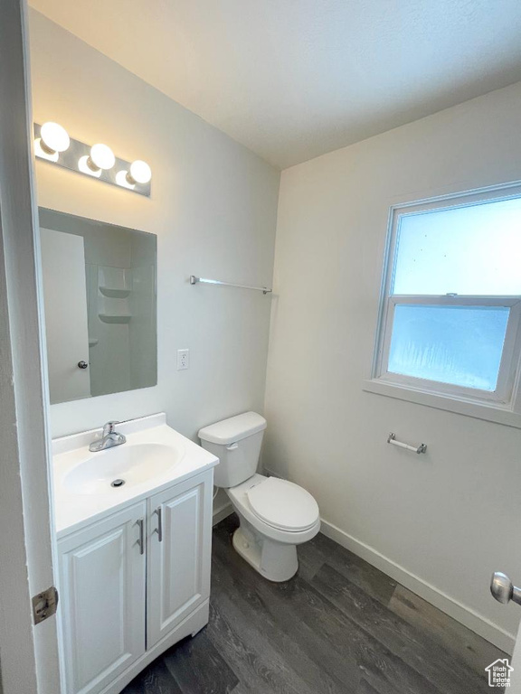 Bathroom featuring wood finished floors, vanity, toilet, and baseboards