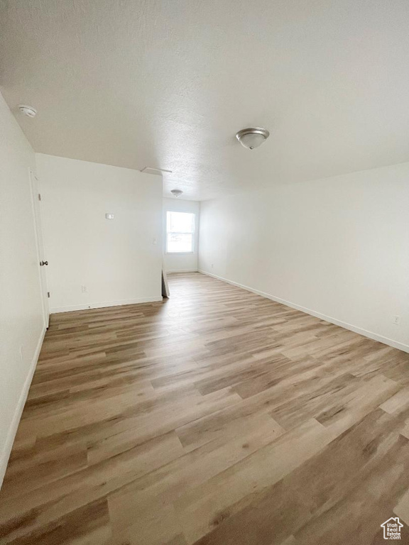 Spare room featuring light wood-type flooring, baseboards, and a smoke detector