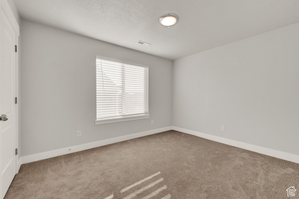 Carpeted spare room featuring baseboards