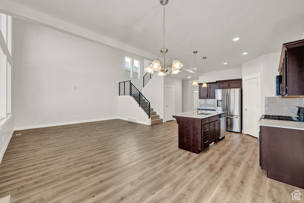 Kitchen with stainless steel appliances, a sink, light countertops, decorative backsplash, and recessed lighting