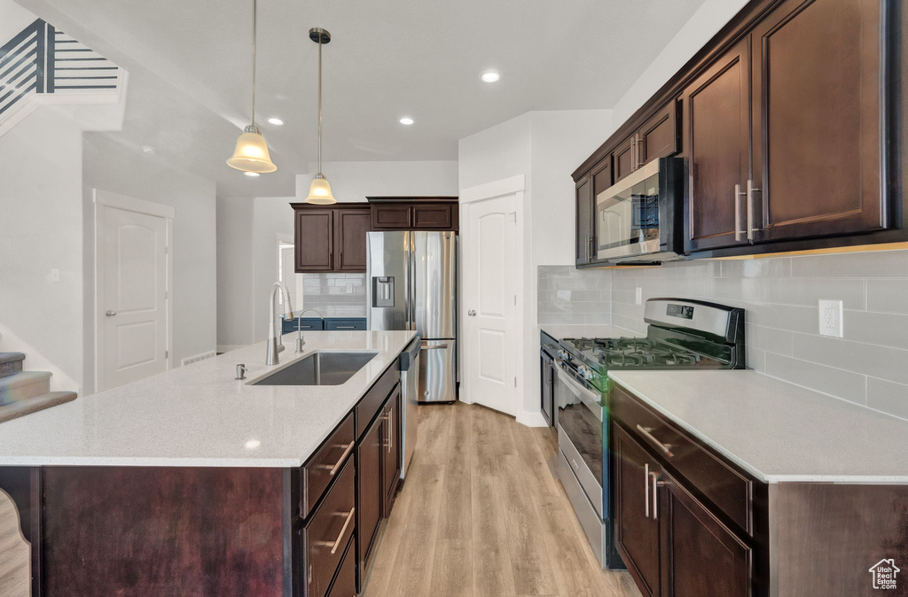 Kitchen with stainless steel appliances, a sink, light wood finished floors, tasteful backsplash, and recessed lighting
