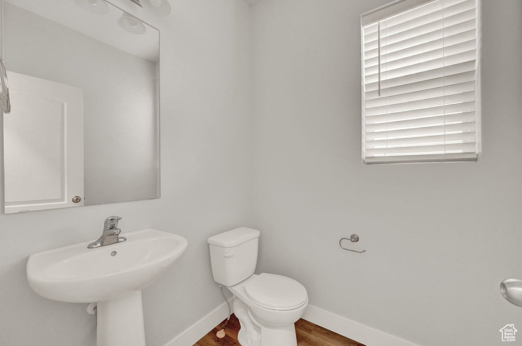 Bathroom featuring baseboards, toilet, and wood finished floors