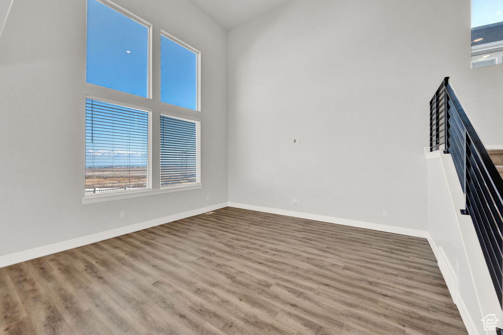 Unfurnished room with healthy amount of natural light, wood finished floors, and baseboards