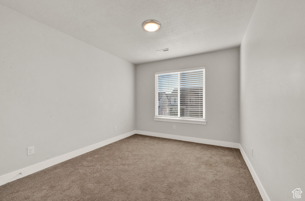 Unfurnished room with carpet flooring, baseboards, and a textured ceiling