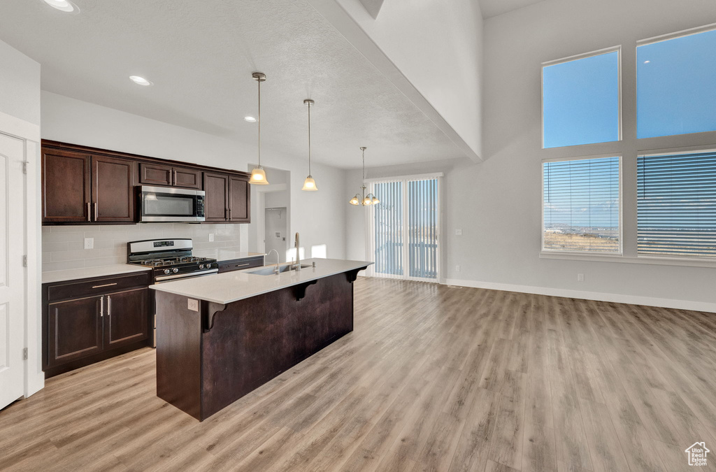 Kitchen featuring appliances with stainless steel finishes, a sink, light wood finished floors, a kitchen breakfast bar, and recessed lighting