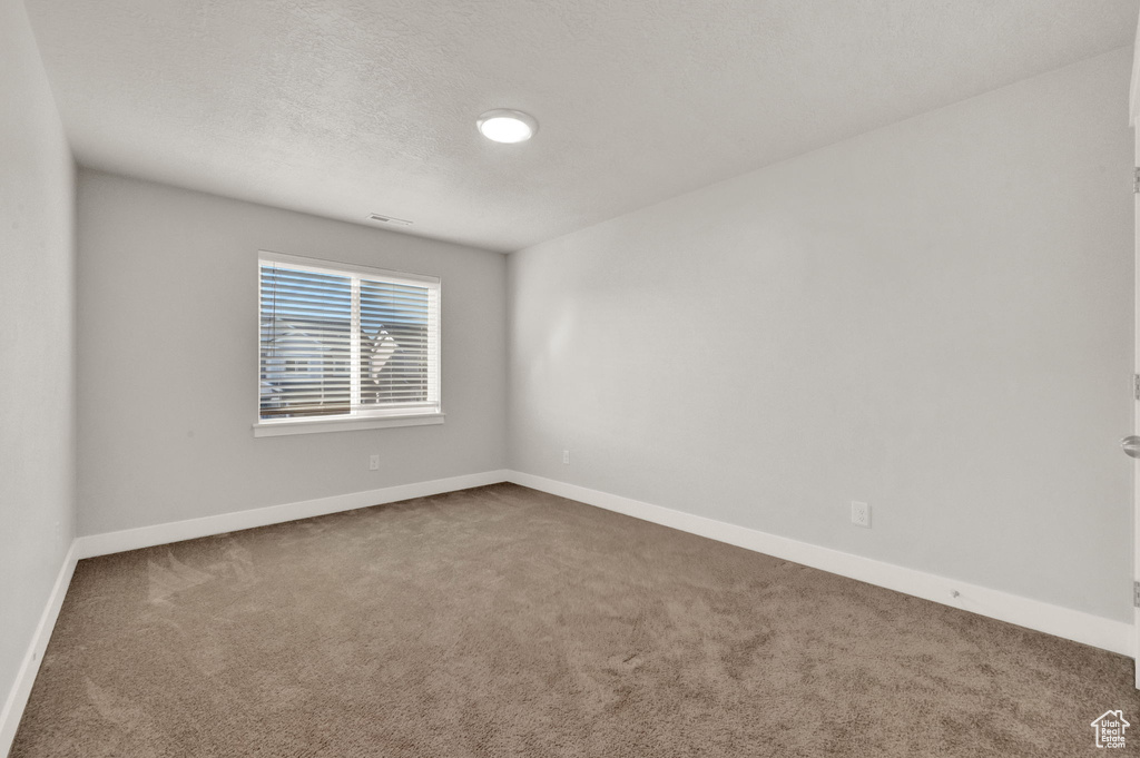 Carpeted empty room with baseboards and a textured ceiling