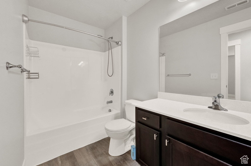 Bathroom with wood finished floors, vanity, toilet, and shower / washtub combination