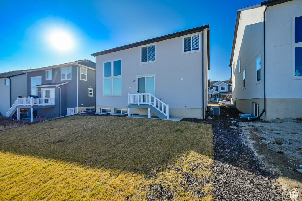 Back of property featuring a yard, a residential view, central AC unit, and stucco siding