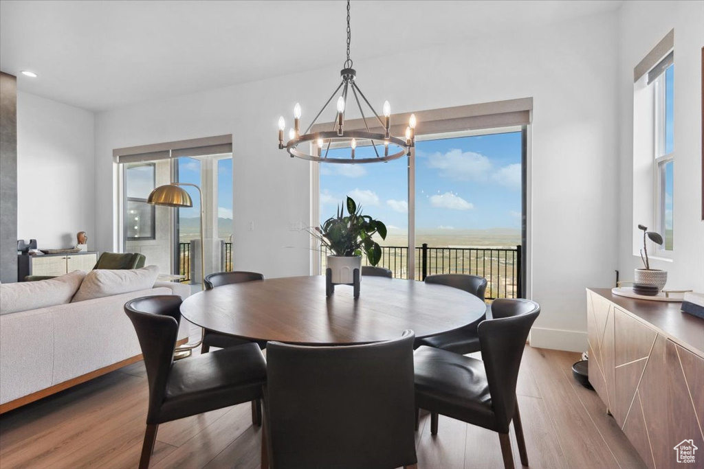 Dining area with light wood finished floors, a chandelier, plenty of natural light, and baseboards