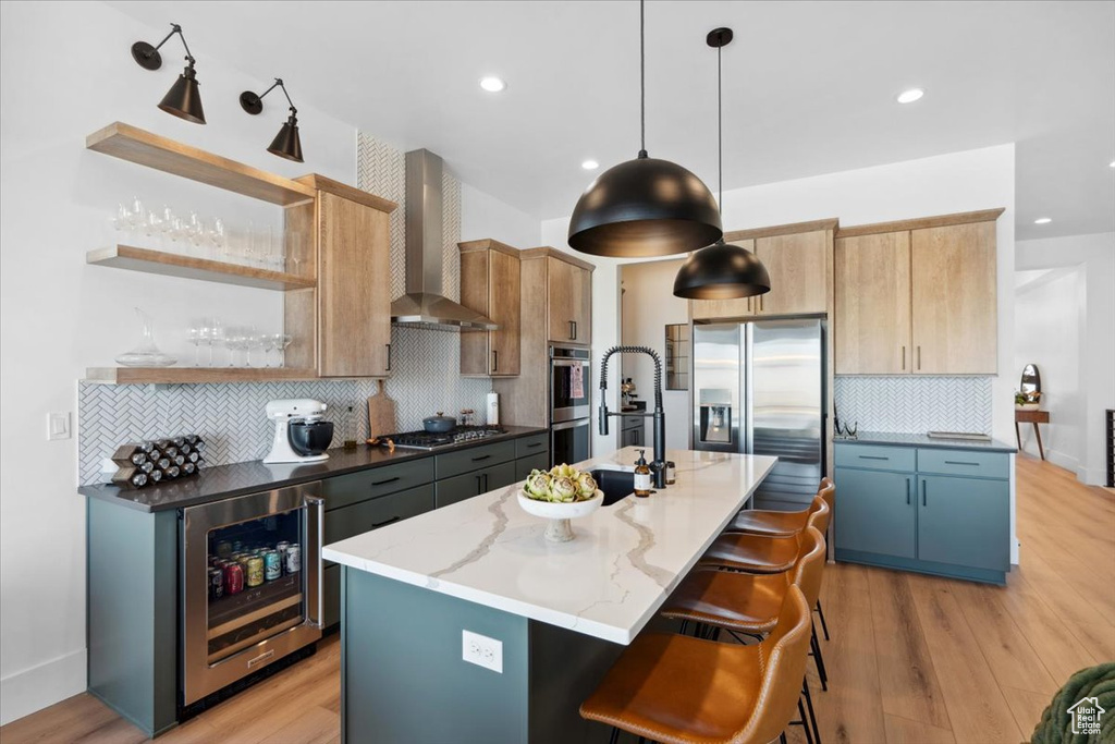 Kitchen with wall chimney range hood, appliances with stainless steel finishes, beverage cooler, tasteful backsplash, and open shelves