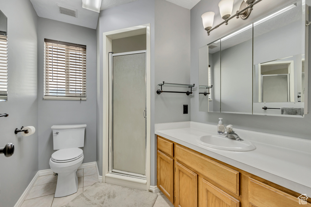 Full bath featuring a shower stall, vanity, toilet, baseboards, and tile patterned flooring