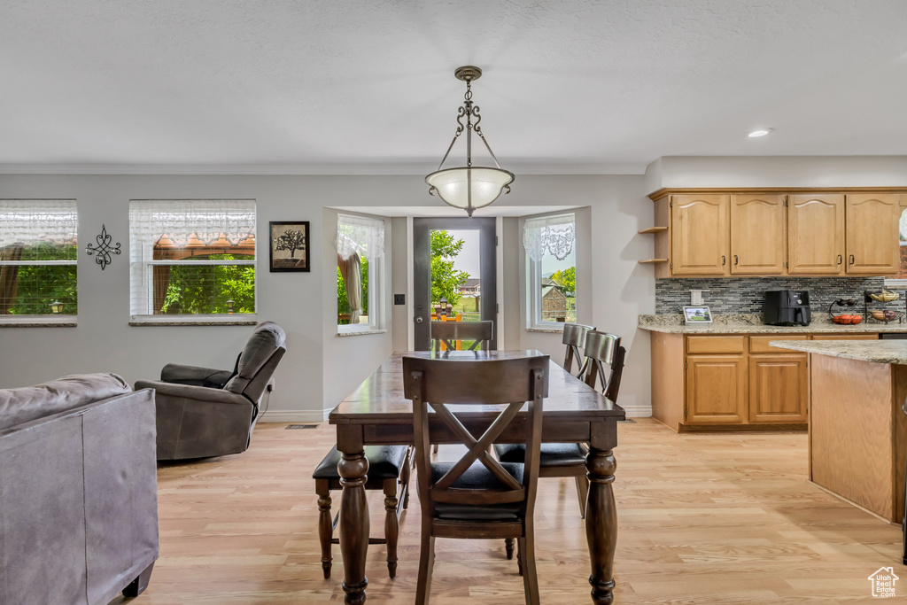 Dining space with light wood-style floors, crown molding, baseboards, and recessed lighting