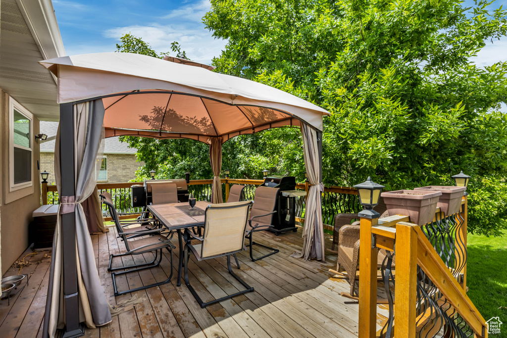 Wooden deck featuring outdoor dining space and a gazebo