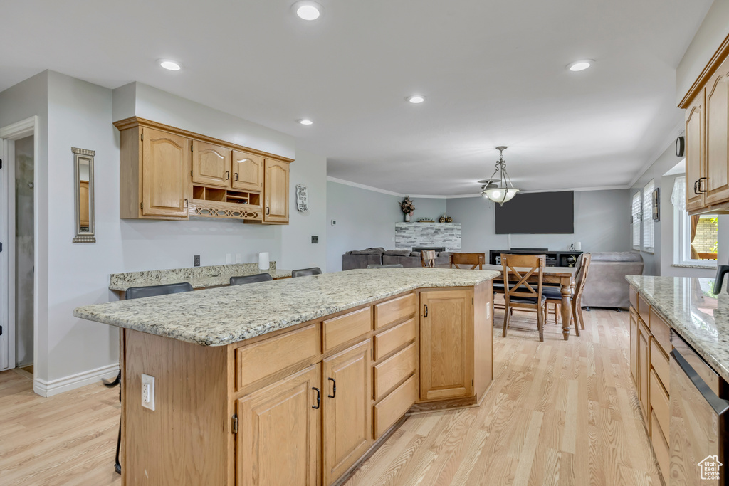 Kitchen with stainless steel dishwasher, open floor plan, light wood finished floors, a kitchen island, and light stone counters