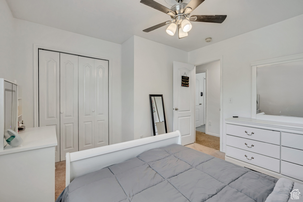 Bedroom featuring light colored carpet, a closet, a ceiling fan, and baseboards