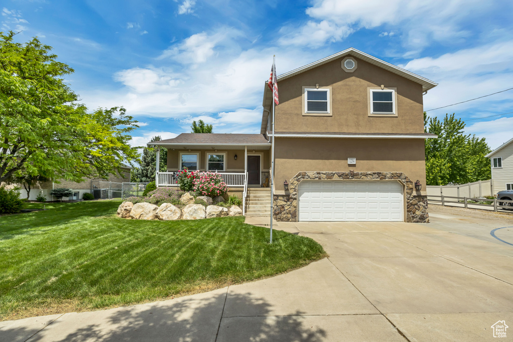 View of front of home featuring stucco siding, an attached garage, driveway, covered porch, and stone siding