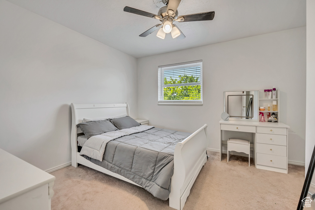 Bedroom with light carpet, baseboards, and a ceiling fan