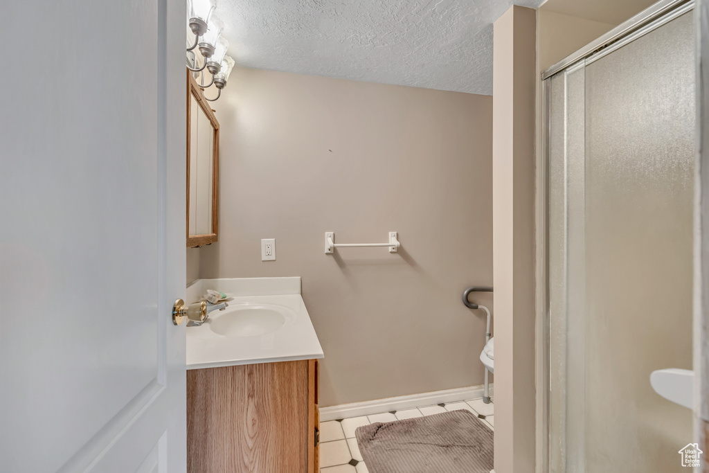 Bathroom featuring vanity, tile patterned floors, a shower stall, toilet, and baseboards
