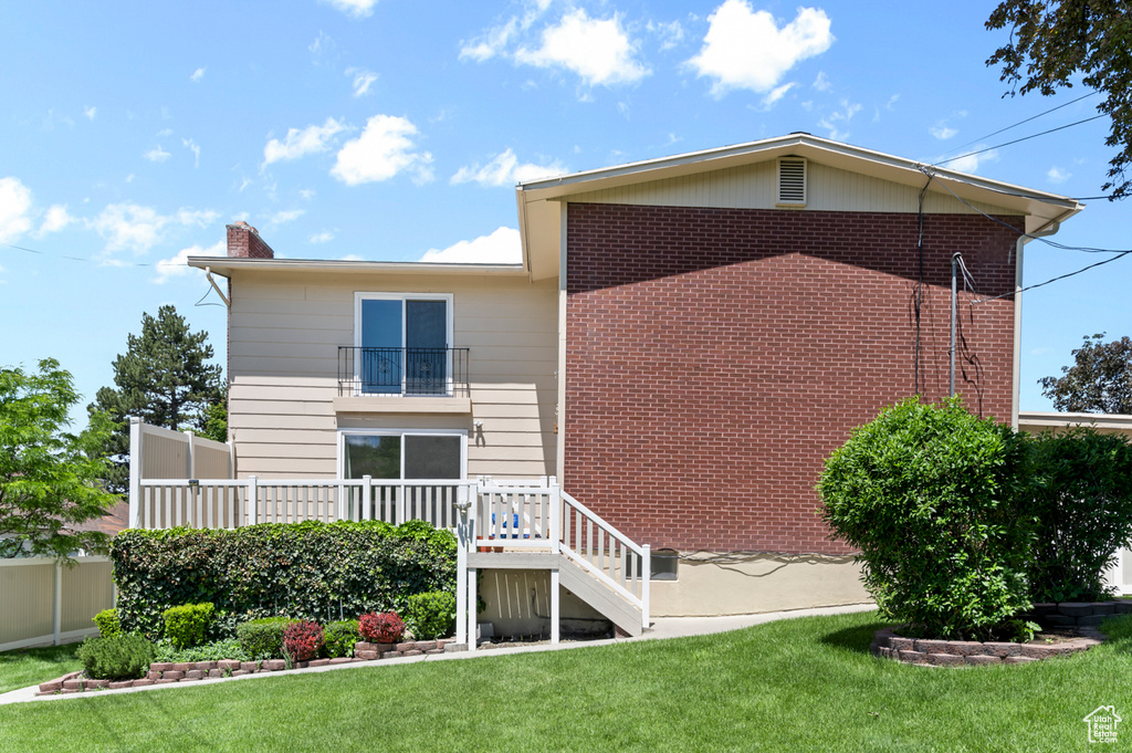 Back of property featuring a balcony, a chimney, and stairway