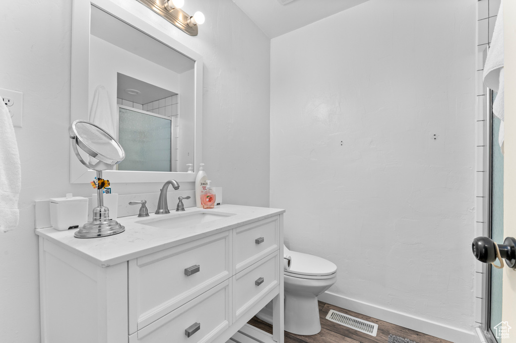 Bathroom featuring vanity, an enclosed shower, toilet, and wood finished floors