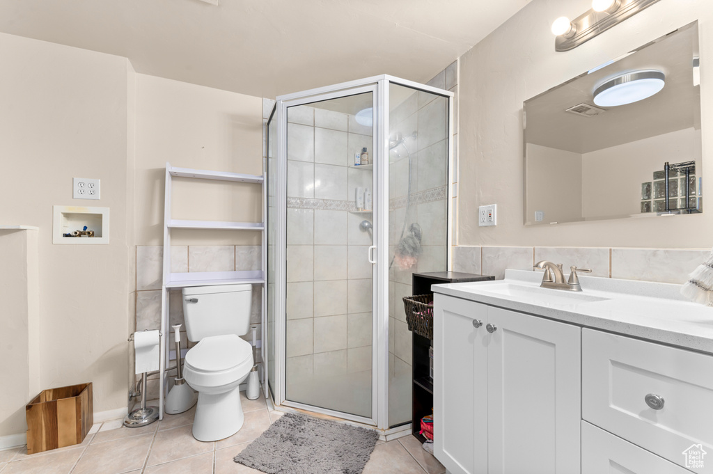 Bathroom featuring vanity, tile patterned floors, a stall shower, and toilet