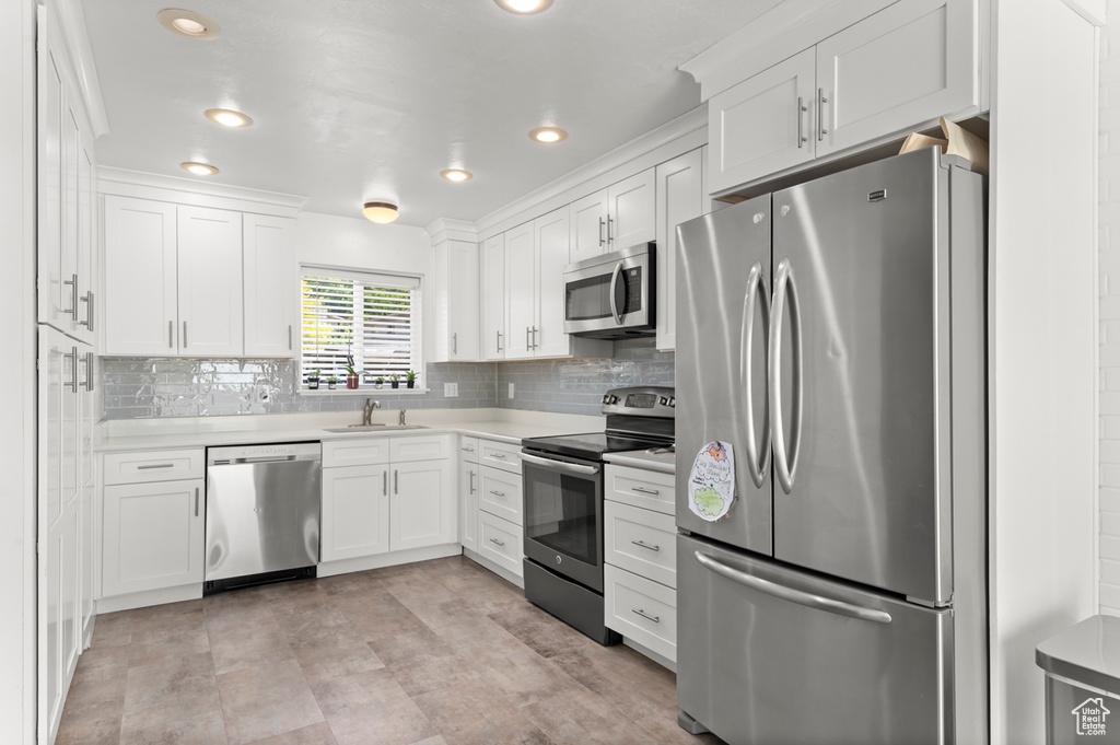 Kitchen with appliances with stainless steel finishes, a sink, white cabinetry, and recessed lighting