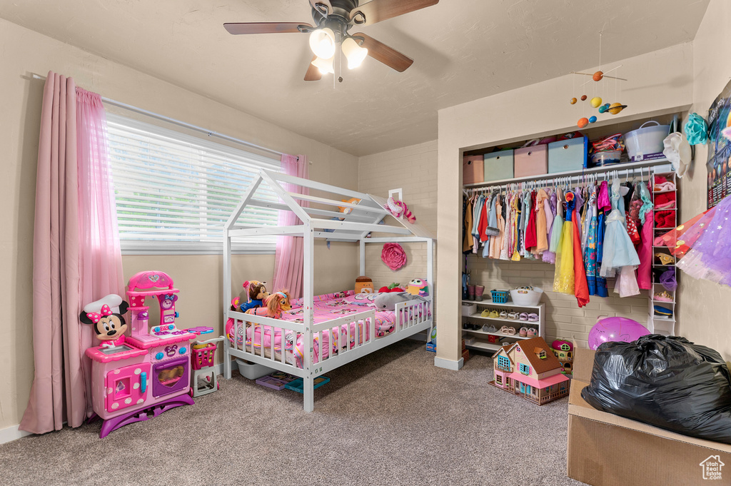 Carpeted bedroom featuring ceiling fan and a closet