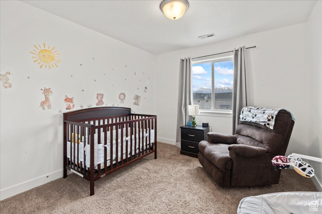Bedroom with carpet, baseboards, and a nursery area