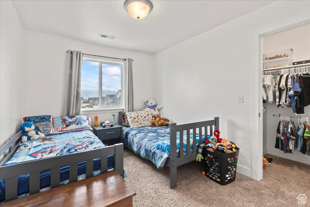 Carpeted bedroom with a closet, a walk in closet, and baseboards