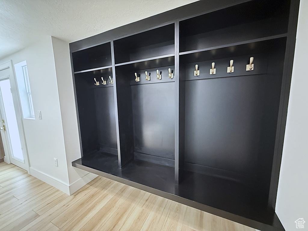 Mudroom with wood finished floors, baseboards, and a textured ceiling