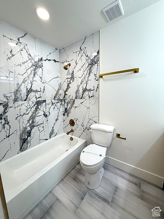 Full bath featuring  shower combination, toilet, and a textured ceiling
