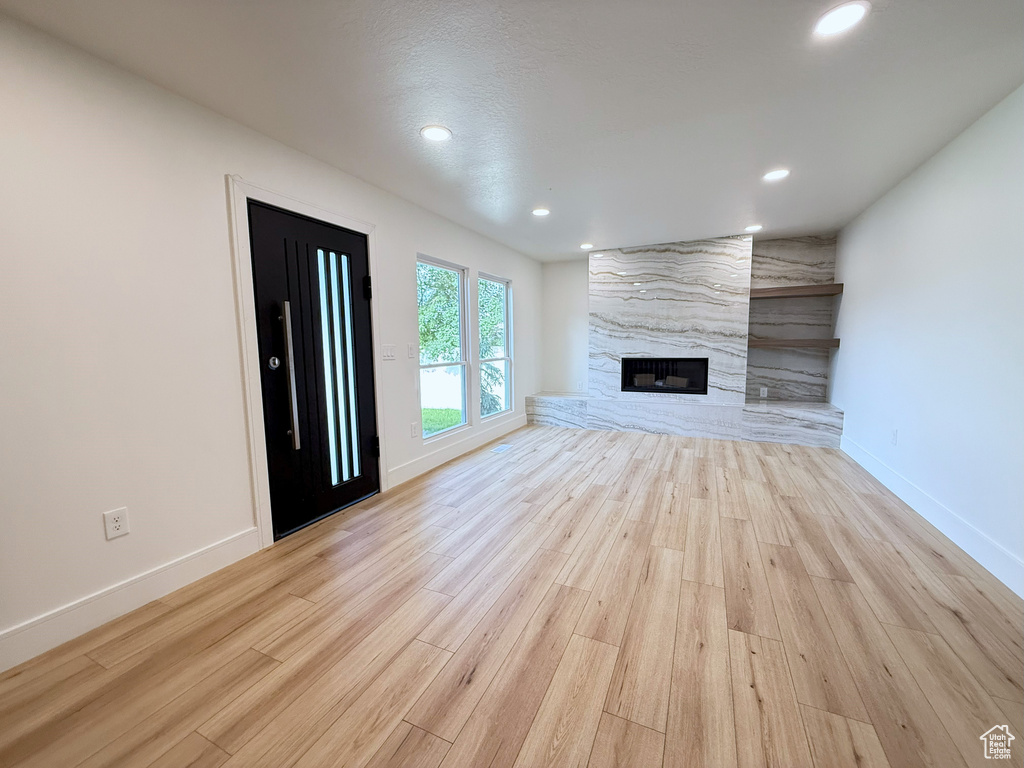 Unfurnished living room with wood finished floors, baseboards, recessed lighting, and a premium fireplace
